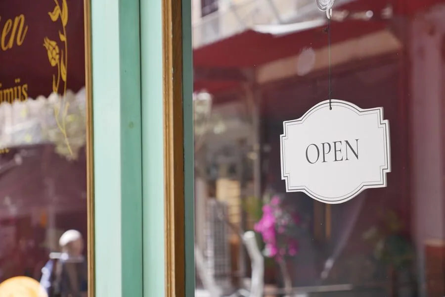 An open sign on a storefront door during the day.